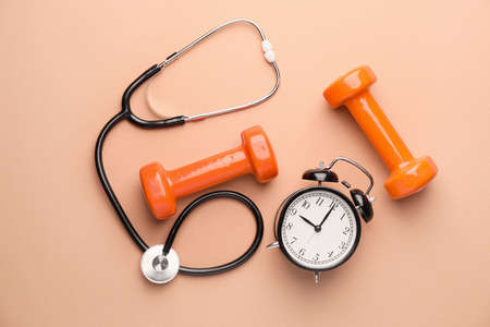 Stethoscope, clock and dumbbells on color backgroundの写真素材