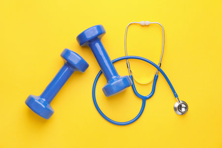 Stethoscope and dumbbells on color backgroundの写真素材