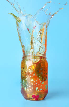Mason jar of cold tea with splashes on color backgroundの写真素材