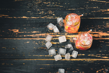 Mason jars of cold tea on dark wooden tableの写真素材