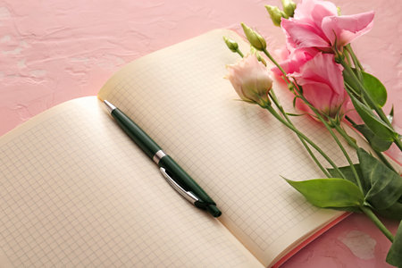 Notebook with pen and flowers on color backgroundの写真素材