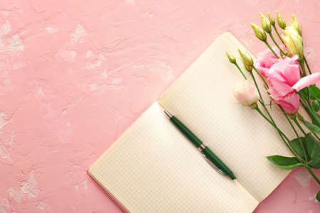 Notebook with pen and flowers on color backgroundの写真素材