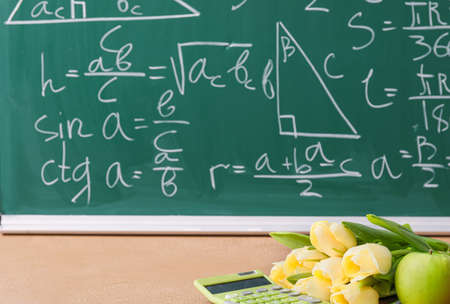 Flowers, calculator and apple on table in classroom. Teacher's day celebrationの写真素材
