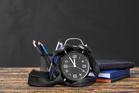 Set of school stationery and clock on table in classroomの写真素材