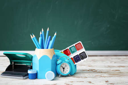 Set of school stationery and clock on table in classroomの写真素材