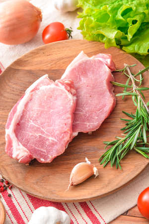 Plate with raw pork meat and vegetables on tableの写真素材