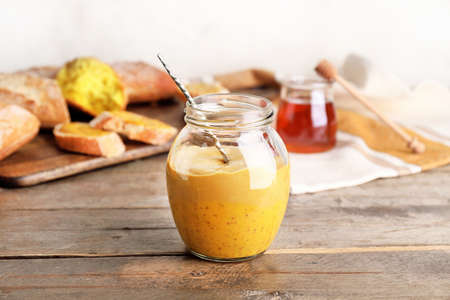 Jar of tasty honey mustard sauce on wooden tableの写真素材