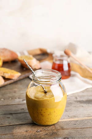 Jar of tasty honey mustard sauce on wooden tableの写真素材