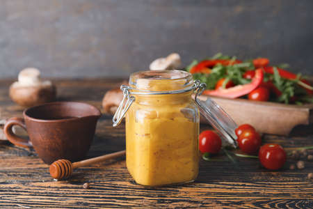 Jar of tasty honey mustard sauce on wooden tableの写真素材