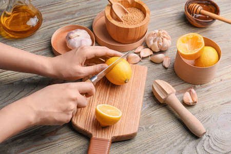 Woman preparing tasty honey mustard sauce on wooden tableの写真素材