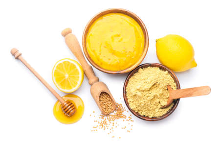 Bowl of tasty honey mustard sauce with ingredients on white backgroundの写真素材