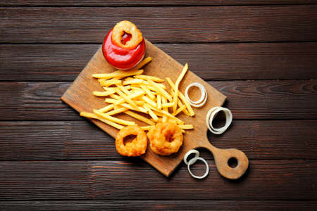 Crispy onion rings, french fries and sauce on tableの写真素材