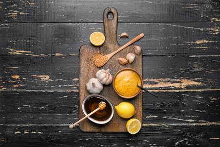 Bowl of tasty honey mustard sauce with ingredients on dark wooden backgroundの写真素材