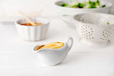 Gravy boat of tasty honey mustard sauce on white wooden tableの写真素材
