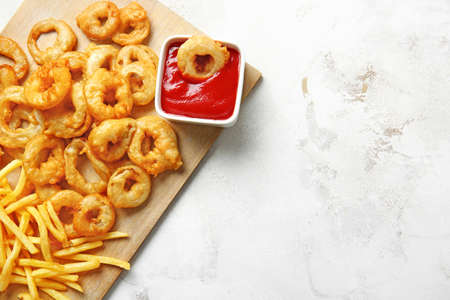 Crispy onion rings, french fries and sauce on tableの写真素材