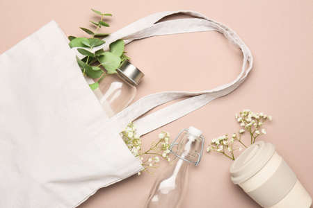 Eco shopping bag with glass bottles and thermo cup on color backgroundの写真素材