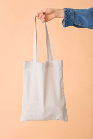 Female hand with eco bag on color backgroundの写真素材