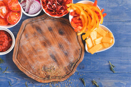 Ingredients for tasty pizza and board on wooden backgroundの写真素材