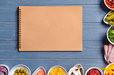 Ingredients for tasty pizza and notebook on wooden backgroundの写真素材