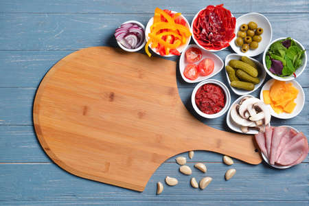 Ingredients for tasty pizza and board on wooden backgroundの写真素材