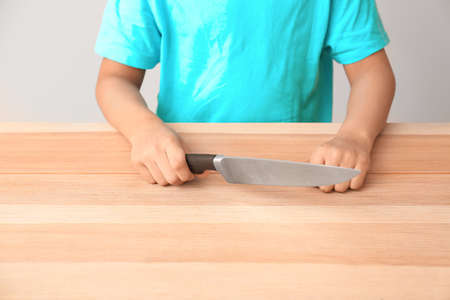 Little African-American boy with knife at table. Child in dangerの写真素材