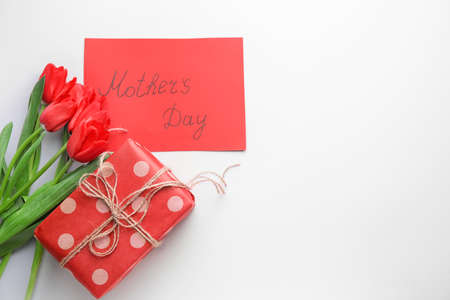 Bouquet of beautiful flowers, card and gift for Mother's Day on white backgroundの写真素材