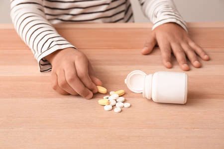 Little African-American boy with pills at table. Child in dangerの写真素材