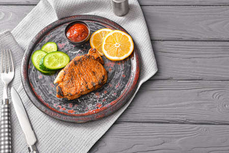 Plate with cooked pork steak and sauce on wooden backgroundの写真素材