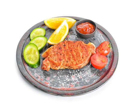 Plate with cooked pork steak, vegetables and sauce on white backgroundの写真素材