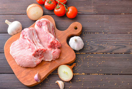 Raw pork meat with vegetables on wooden backgroundの写真素材
