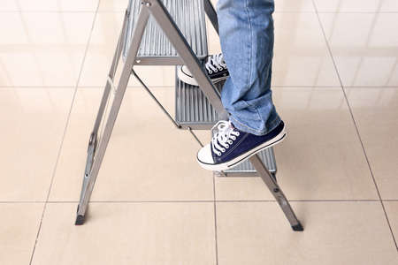 Little African-American boy playing with step ladder at home. Child in dangerの写真素材
