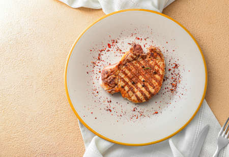 Plate with cooked pork steak and spices on color backgroundの写真素材