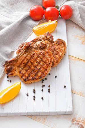 Board with cooked pork steaks on tableの写真素材