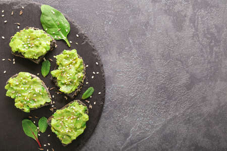 Slate plate with tasty avocado sandwiches on dark backgroundの写真素材