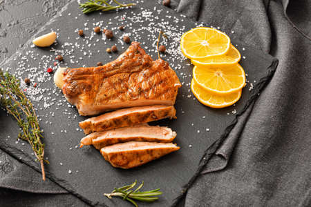 Cooked pork steak and spices on slate plateの写真素材
