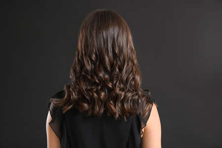 Young woman with beautiful curly hair on dark backgroundの写真素材