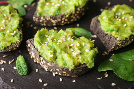 Tasty avocado sandwiches on slate plate, closeup