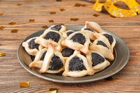 Plate with tasty hamantaschen for Purim holiday on wooden backgroundの写真素材