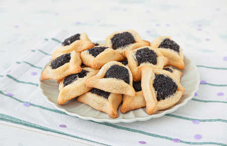 Plate with tasty hamantaschen for Purim holiday on tableの写真素材