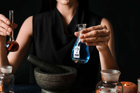 Female alchemist making potion on dark backgroundの写真素材