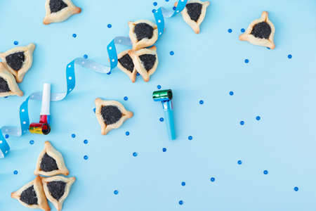Tasty hamantaschen and party decor for Purim holiday on color backgroundの写真素材