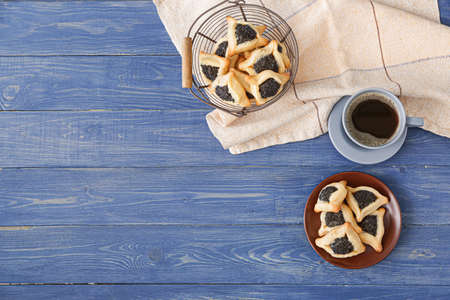 Tasty hamantaschen for Purim holiday and cup of coffee on tableの写真素材
