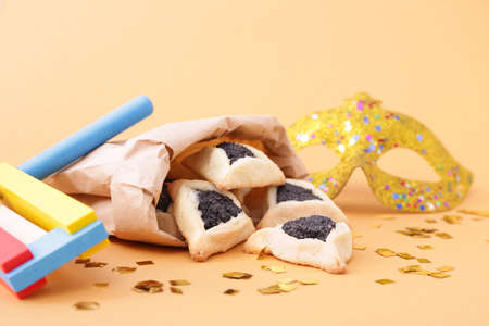 Tasty hamantaschen, gragger and party decor for Purim holiday on color backgroundの写真素材