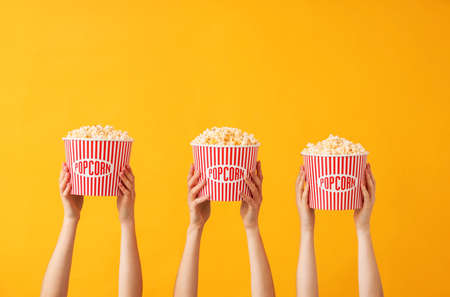 Many hands with popcorn in buckets on color backgroundの写真素材