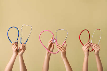 Many hands with stethoscopes on color backgroundの写真素材