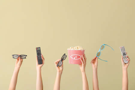 Many hands with popcorn, remote controls and eyeglasses on color backgroundの写真素材