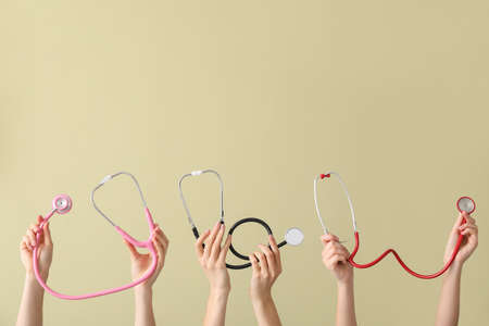 Many hands with stethoscopes on color backgroundの写真素材