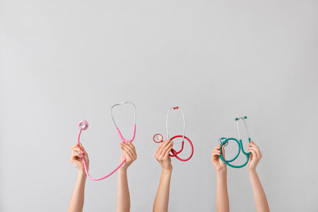 Many hands with stethoscopes on gray backgroundの写真素材