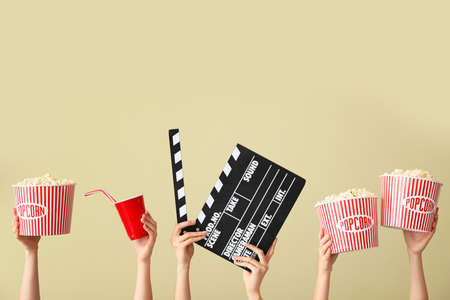 Many hands with popcorn, drink and movie clapper on color backgroundの写真素材