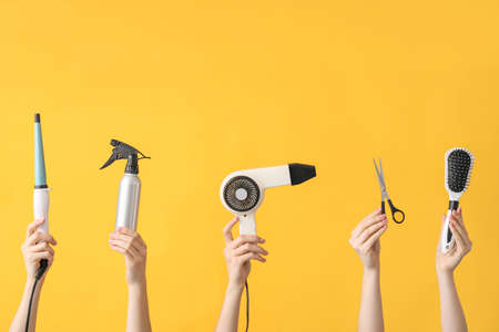 Many hands with hairdresser's supplies on color backgroundの写真素材